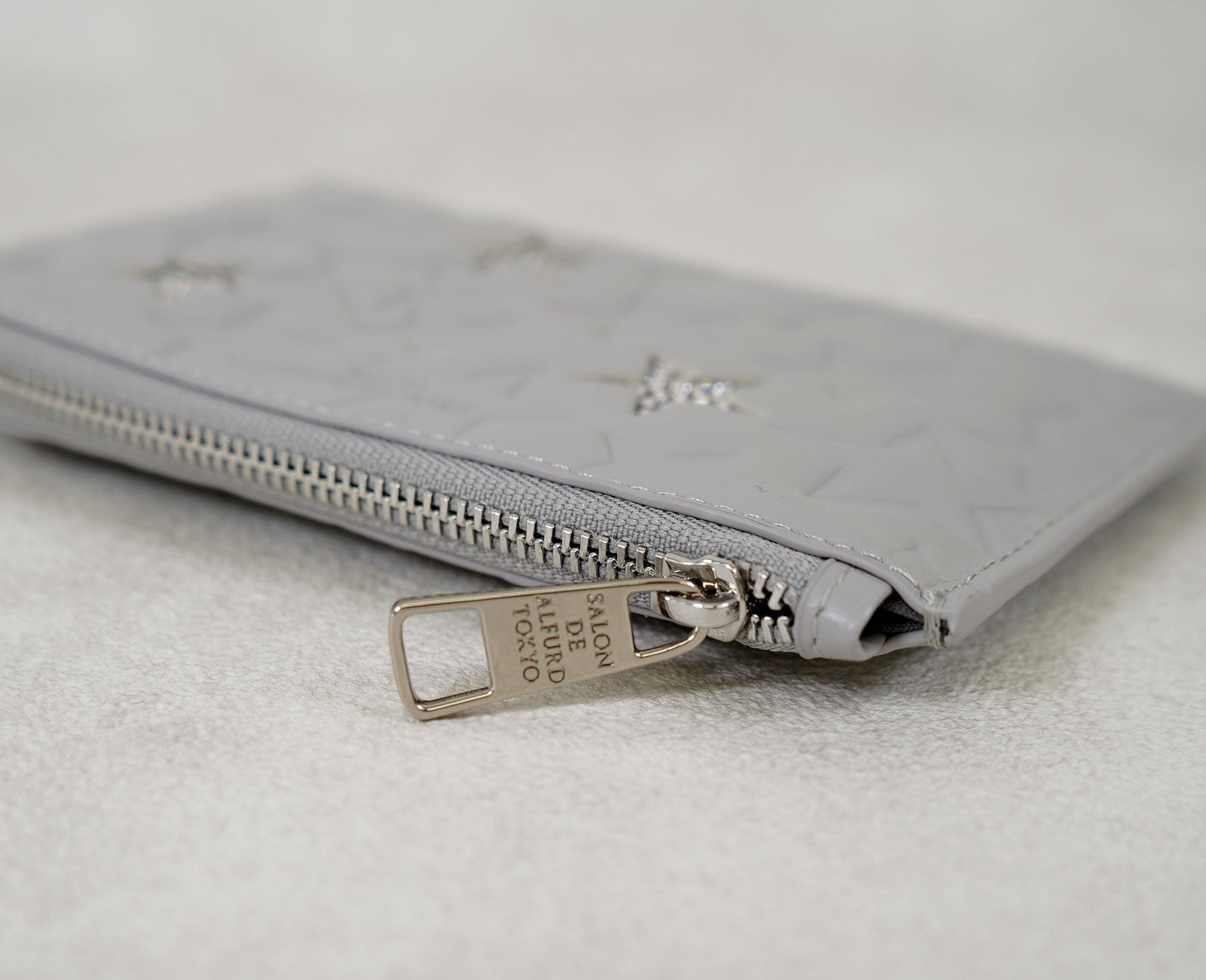 ファスナーチャームには、ブランドネームを刻み、上質な存在感を添えて。