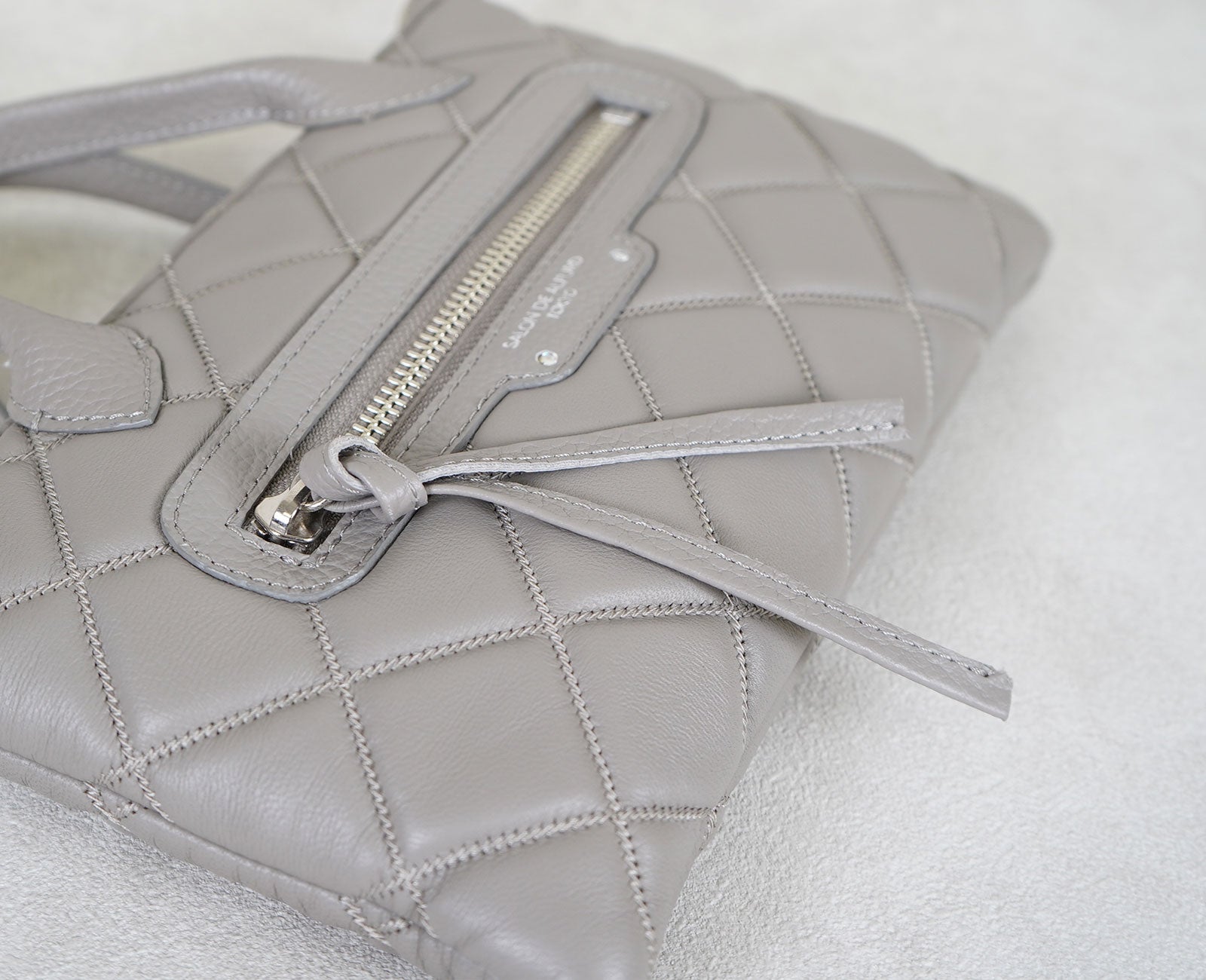 引き手には、シュリンク型押しレザーで仕立てたロングストラップ。軽やかに揺れる姿が愛らしいアクセントに