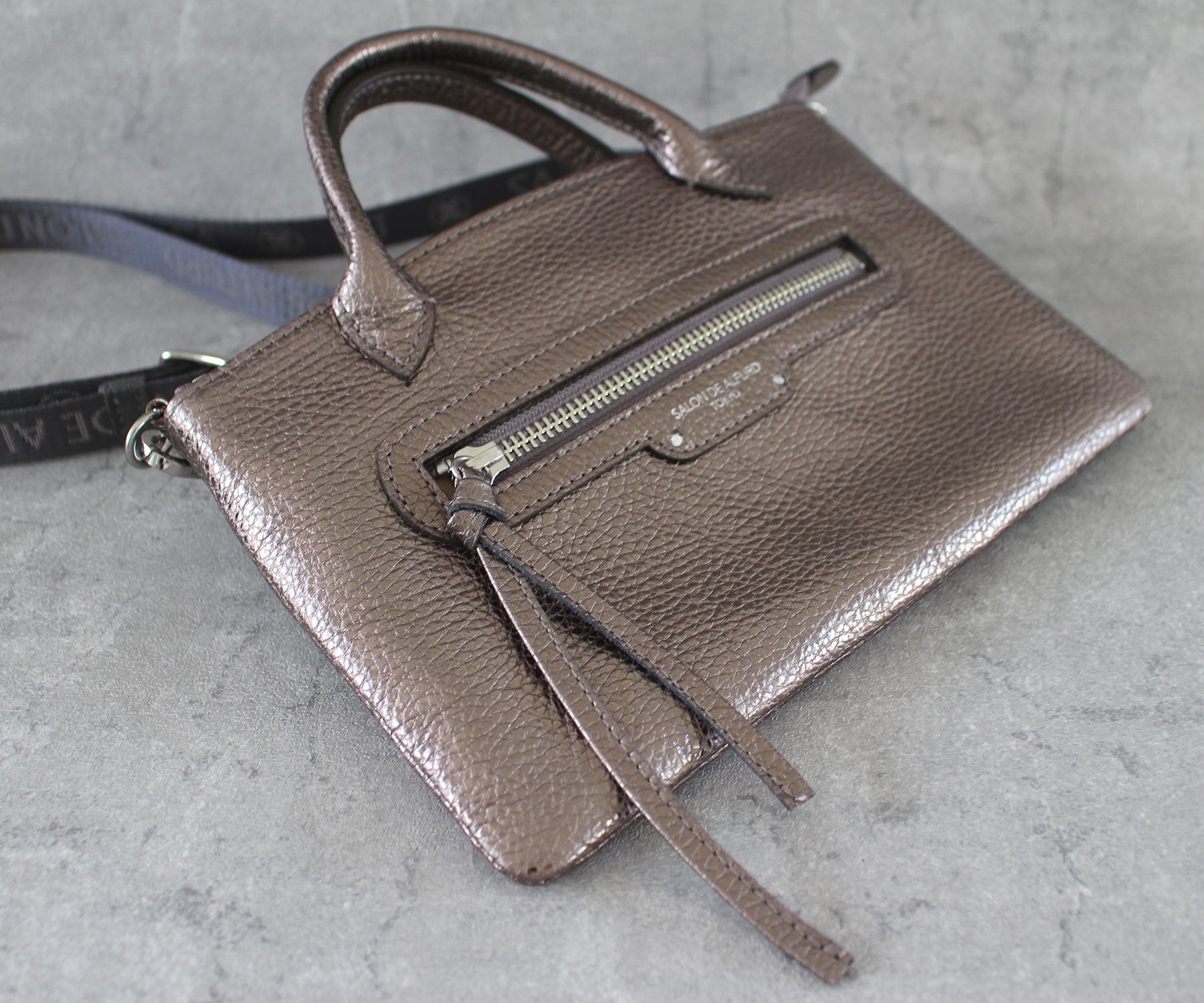 ボディと同素材のイタリアンシュリンク型押しレザーで仕立てたファスナーチャームが、デザインに上質なアクセントを添えます。